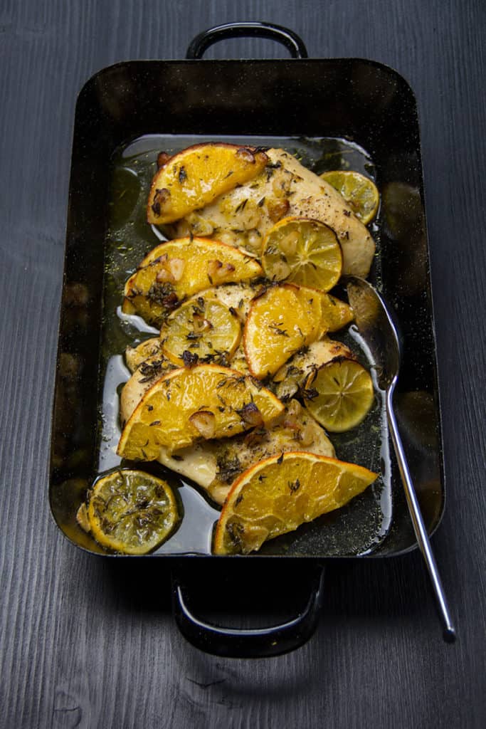 Huhn mit Orangen- und Zitronenscheiben, gewürzt mit Kräutern, Knoblauch und Olivenöl.